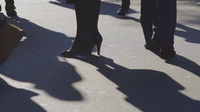 Woman In High Heel Shoes Appearing And Standing In A Crowd Of Passerby Shoes And Shadows On A Shopping Main Street