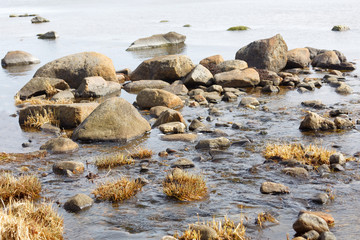 Little creek with stones meet the calm sea a sunny day during the spring