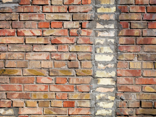 On an old wall of red bricks a separated vertical fragment of the old silicate brick