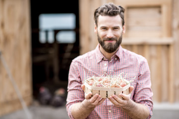 Farmer holding eggs in the wooden pack on the henhouse background. Image focused on the eggs © rh2010
