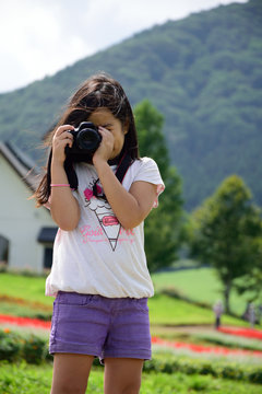 A girl who takes a photograph in summer highland.
