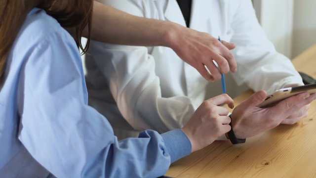 close up of a tablet in a doctors hands discussing medical team work consultation. they indicates by finger on a touch screen 4k