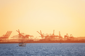 Fototapeta na wymiar Long Beach shipping port with cranes at sunset