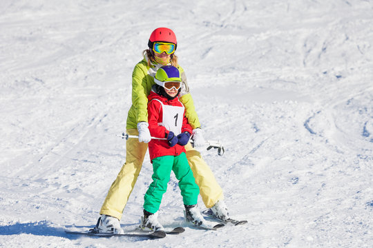 Female trainer teaching boy skiing at sunny day