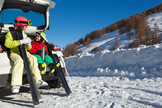 Happy skiers drinking warm tea from thermos