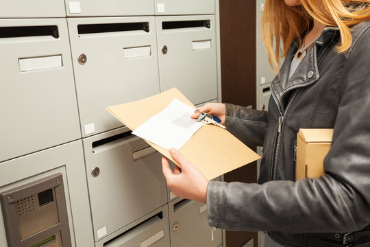 Woman's hands holding blanked envelopes and box