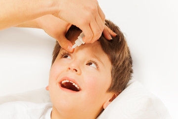 Fototapeta premium Woman helping kid boy to instill eye drops