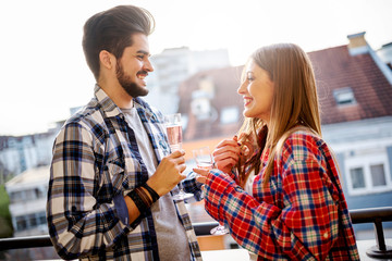 Young  couple having party  on apartment balcony drinking champagne
