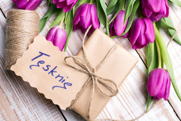 Polish words I MISS YOU and bouquet of tulips on wooden background