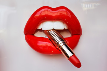 red female lips holding lipstick