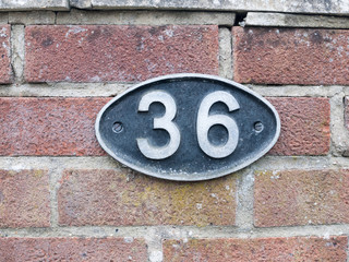 a number plate on a brick wall with 36 on it
