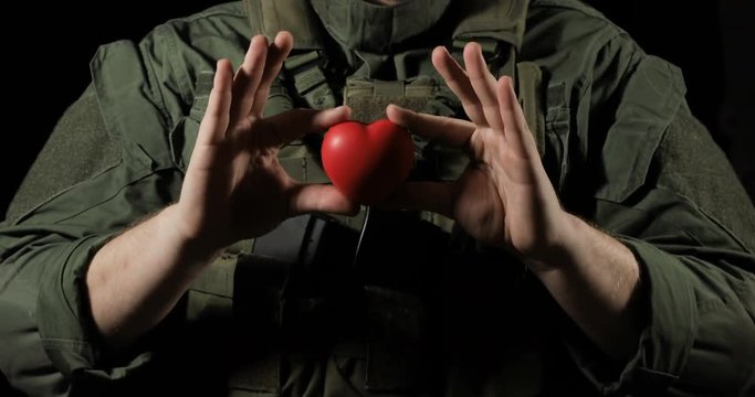 Red heart in the hands of a soldier, concept