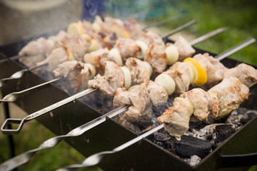 Outdoor BBQ Grill. Barbecue grill flame. Shashlik on skewers closeup, raw and cooked. Juicy slices of meat prepare on fire.