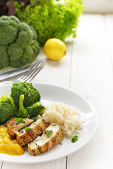 fried chicken breast fillet with  fruit chuntey, broccoli and rice and the ingredients on white wood, vertical