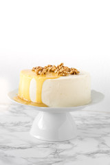 Whole White wedding or Birthday sugar free and gluten free Cake with salty caramel and nuts on marble background. Vegan food concept