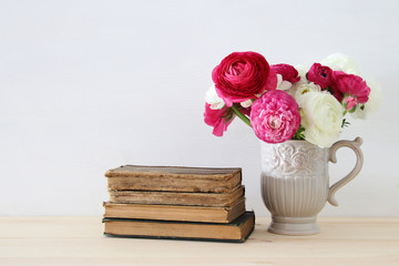 Beautiful bouquet of flowers in the vase next to old books