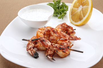 Grilled shrimps on a plate served with white sauce and lemon