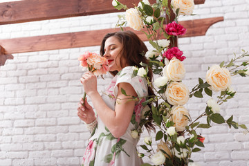 Beautiful young brunette woman dressed in summer dress with flowers