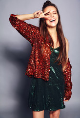 Beautiful caucasian smiling hipster brunette woman model in bright shinny reflecting summer stylish jacket and green dress posing on gray background. Showing peace sign