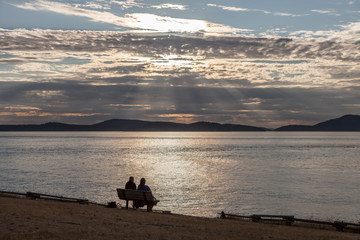 relaxing romance couple on a bench at sunset