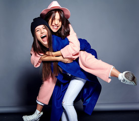 fashion portrait of two smiling brunette women models in summer casual hipster overcoat posing on...