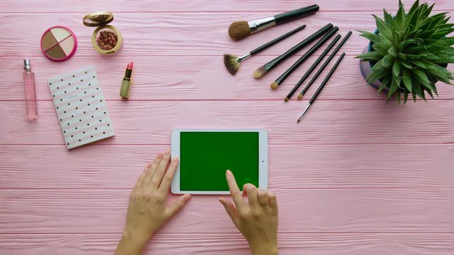 Young woman using tablet on table. Womans hand seraching something on laptop. Green screen. Top view. Chroma key.