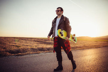 Fototapeta premium Man walking on the street and holding skateboard