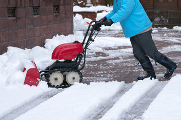 Man cleaning driveway after a snow storm, Snow removal equipment working on the street, Cleaning of...