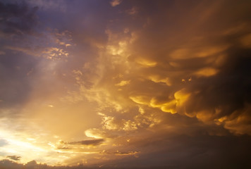 Naklejka na ściany i meble Beautiful dark fluffy cloudy sky with sun rays. Sunset light.
