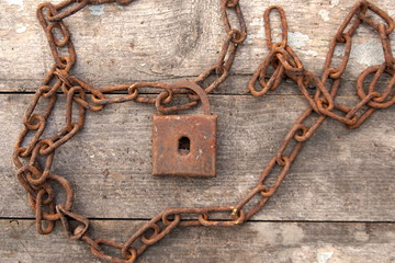 rusty old lock with a chain on a wooden background