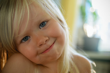 Little blonde girl with blue eyes looks at you