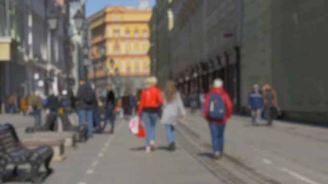 Blurred intentionally, people are walking along the beautiful streets of the city. A beautiful sunny day