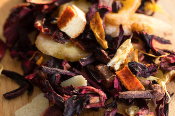 Pile of fruit tea with petals and dry fruit .The composition of the heap of tea leaves and dried hibiscus flower located on a wooden Board. Tea with natural ingredients closeup. Macro photo of tea.