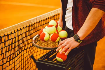 Foto op Canvas hand man holding a tennis racket and a lot of goals. Basket for tennis balls, © Elizaveta