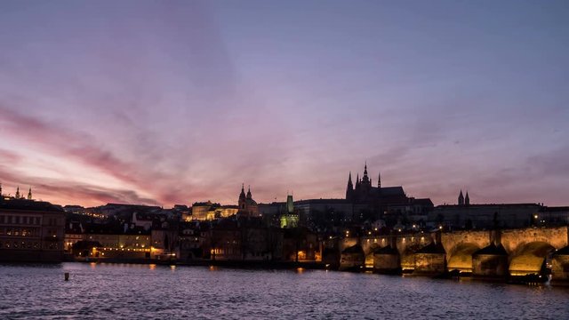 Pisturesque view on the Charles Bridge with an impressive dark red and grey skyscape. streaming ships, sparkling waters of the Vltava river n the evening twilights  being shot as a timelapse