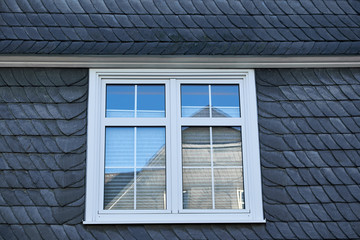 White colonial style window in a black facade covered in black layered slate, typical Winterberg building style