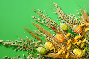 Easter background. Decorative eggs and dry grass on a green background.