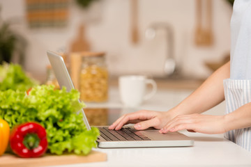 Obraz na płótnie Canvas Girl with laptop on the kitchen. Food blogger concept