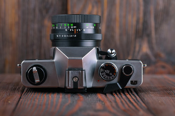 The old 35 mm SLR camera on a wooden background.
