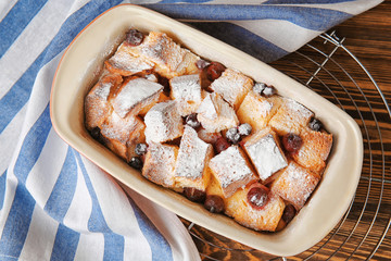 Freshly baked bread pudding in casserole dish on wooden table