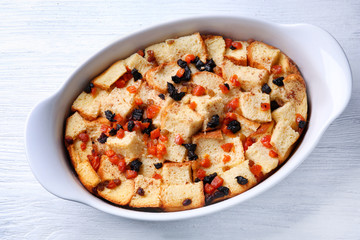Freshly baked bread pudding in casserole dish on wooden table