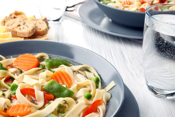 Chicken noodle soup in plate on wooden table, closeup