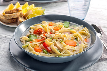 Chicken noodle soup in plate on wooden table, closeup