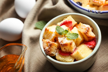 Delicious bread pudding with strawberry in bowl on napkin