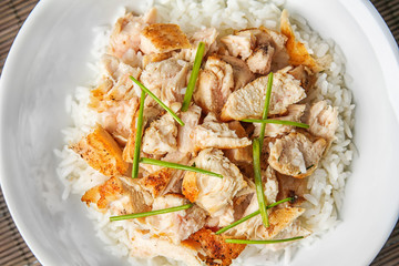 Plate with chicken and rice on wicker mat, closeup