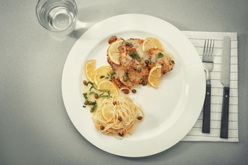 Plate with delicious Italian chicken piccata on table