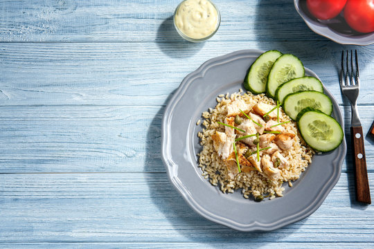 Plate with rice, chicken and vegetables on kitchen table