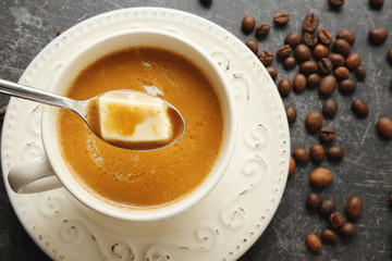 Cup of tasty butter coffee and spoon on grey background