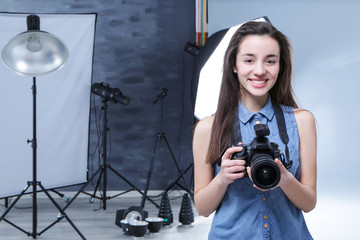 Young professional photographer with camera in studio