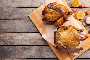 Board with roasted beer can chickens on wooden background